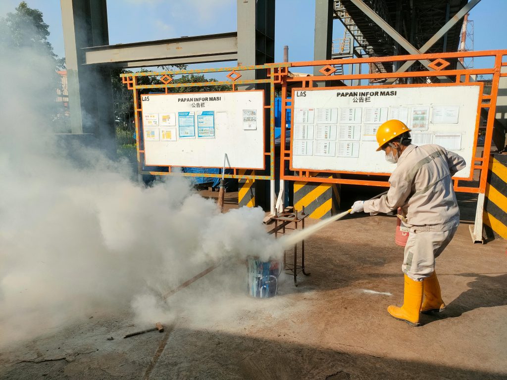 Worker conducts fire safety training outdoors with extinguishers.