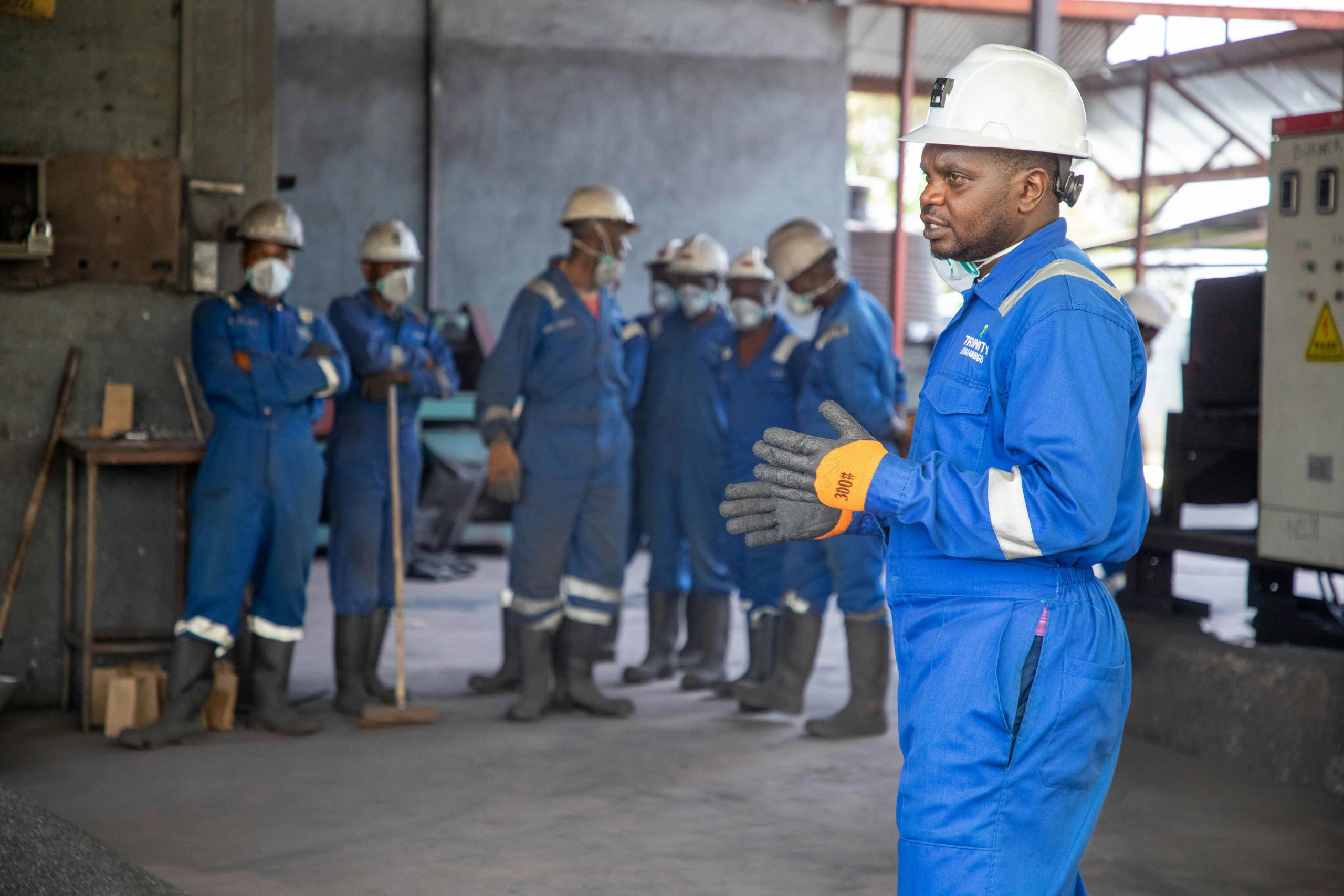 A group of factory workers in safety gear receiving training indoors.